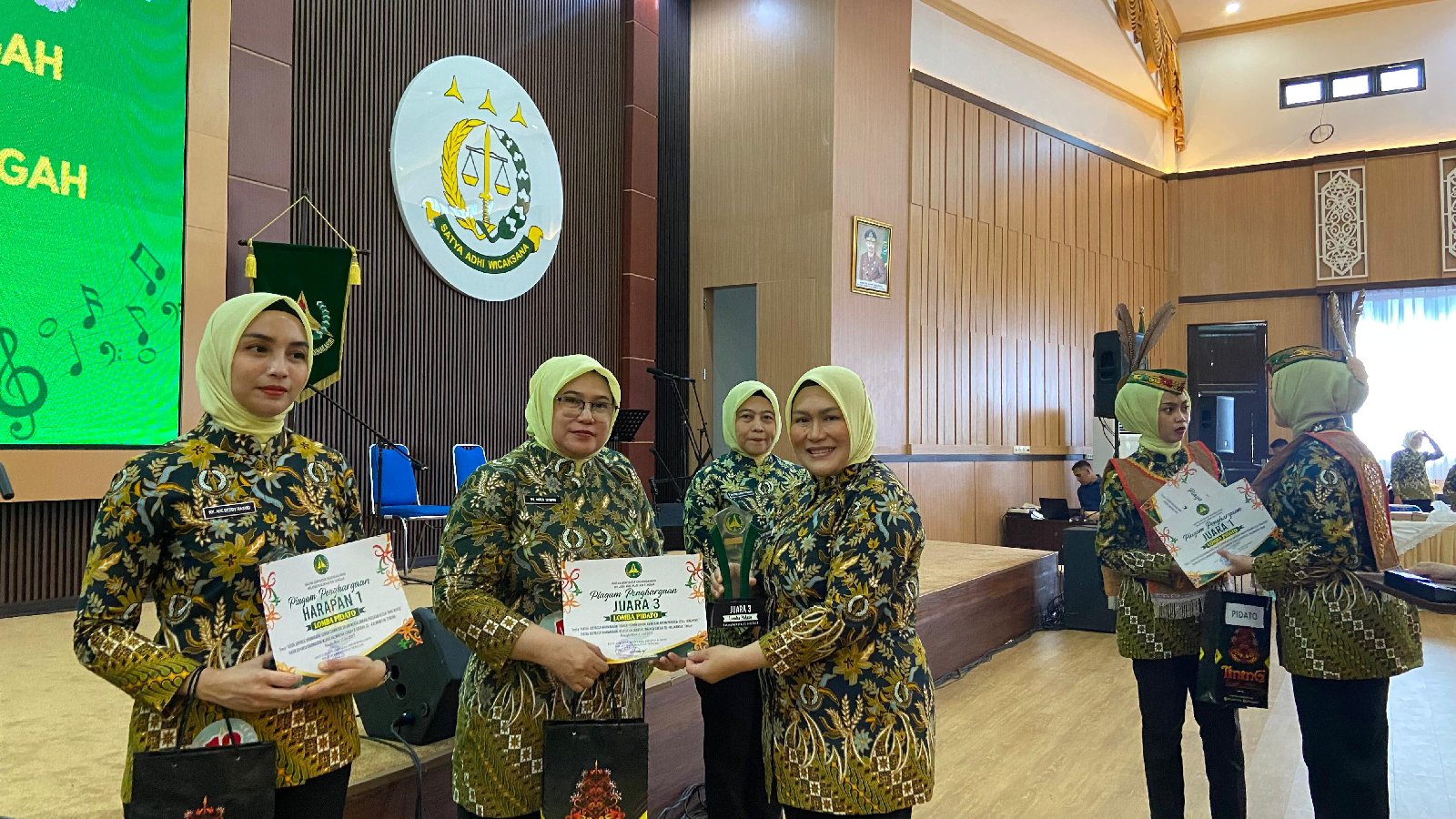 Sekelompok wanita mengenakan pakaian batik dan hijab menerima sertifikat di sebuah acara resmi. Sekelompok wanita mengenakan pakaian batik dan hijab menerima sertifikat di sebuah acara resmi.