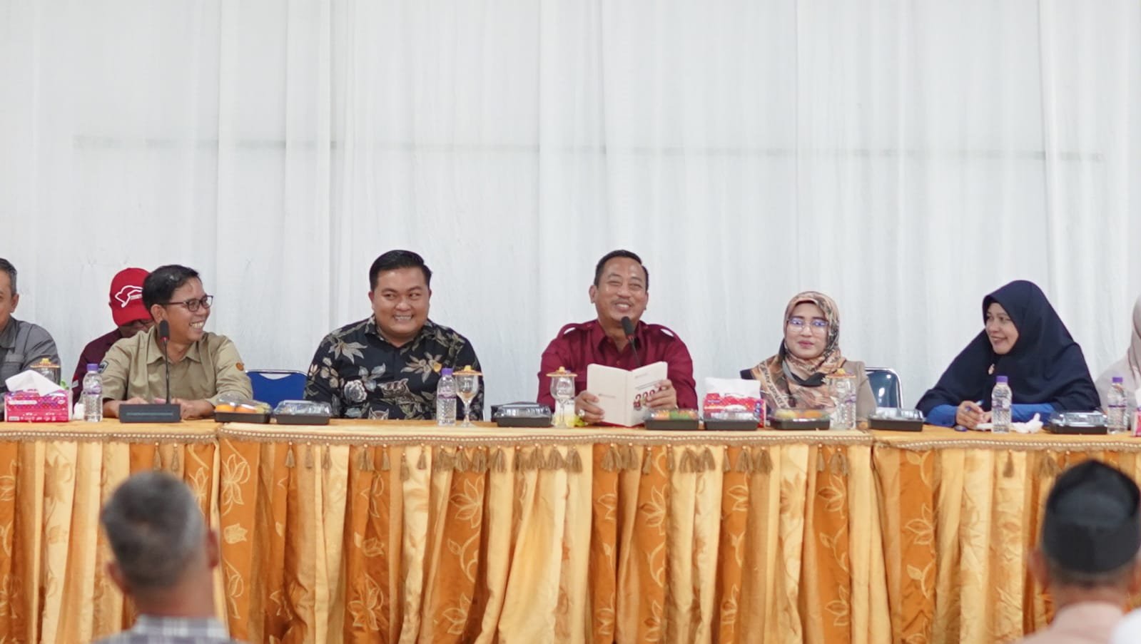 Sejumlah orang duduk di meja panjang dalam sebuah pertemuan, dengan satu orang membaca buku. Sejumlah orang duduk di meja panjang dalam sebuah pertemuan, dengan satu orang membaca buku.