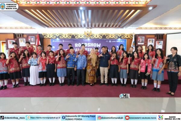 Sekelompok peserta Roadshow Festival Literasi Harati Pemkab Murung Raya berfoto bersama dengan pakaian bernuansa batik merah di aula.