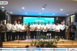 Suasana Rakernas APKASI XVII dengan Heriyus, Sarman Simanjorang, dan Delis Julkarson Hehi berdiri di depan panggung, berlatar layar biru.