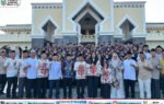 Rombongan 73 jamaah calon haji bersama Heriyus dan Pirman Prihatin berpose di depan Masjid Agung Puruk Cahu, mengenakan batik dan topi haji.