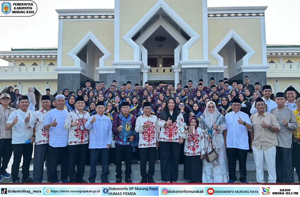 Rombongan 73 jamaah calon haji bersama Heriyus dan Pirman Prihatin berpose di depan Masjid Agung Puruk Cahu, mengenakan batik dan topi haji.