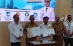 Sekelompok pejabat menyodorkan dokumen nota serah terima dalam acara BPJN, dipimpin H M Noor Rifani, dengan kemeja putih dan seragam cokelat.