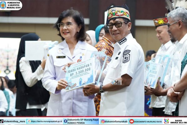 Heriyus menerima tiga penghargaan stunting Kalteng 2026 dengan sertifikat dari Linae Victoria Aden di aula, berpakaian putih dan kopiah bermotif.