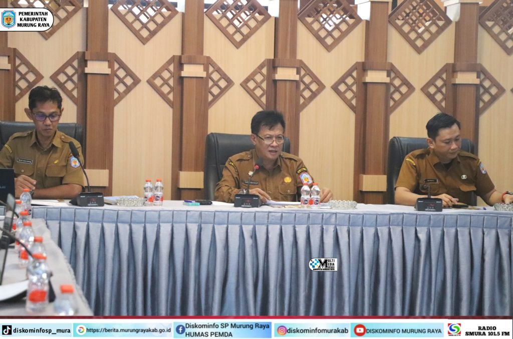 Rapat desk rencana penyaluran TDF Tahap I Pemkab Murung Raya berlangsung di aula Bapperida, Sarwo Mintarjo memimpin dengan seragam cokelat di meja rapat.
