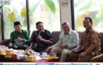 Suasana pertemuan Camat se-Kab. Murung Raya di Hotel Dandang Tingang, menampilkan Bupati Heriyus dan Rahmanto Muhidin dengan pakaian batik, tersenyum.