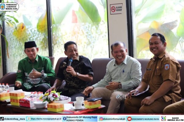 Suasana pertemuan Camat se-Kab. Murung Raya di Hotel Dandang Tingang, menampilkan Bupati Heriyus dan Rahmanto Muhidin dengan pakaian batik, tersenyum.