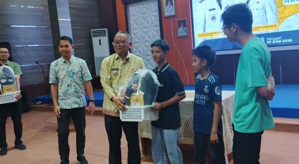 Bupati Tabalong H. Noor Rifani menyerahkan beasiswa dan perlengkapan sekolah kepada tiga anak korban kebakaran di Gedung Informasi Tabalong.