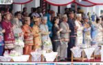 Para pejabat dan tamu undangan berdiri berbaris dengan busana adat saat Upacara Hari Jadi ke-24 Kabupaten Gunung Mas di halaman kantor bupati.