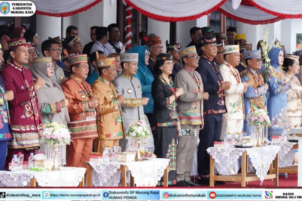 Para pejabat dan tamu undangan berdiri berbaris dengan busana adat saat Upacara Hari Jadi ke-24 Kabupaten Gunung Mas di halaman kantor bupati.