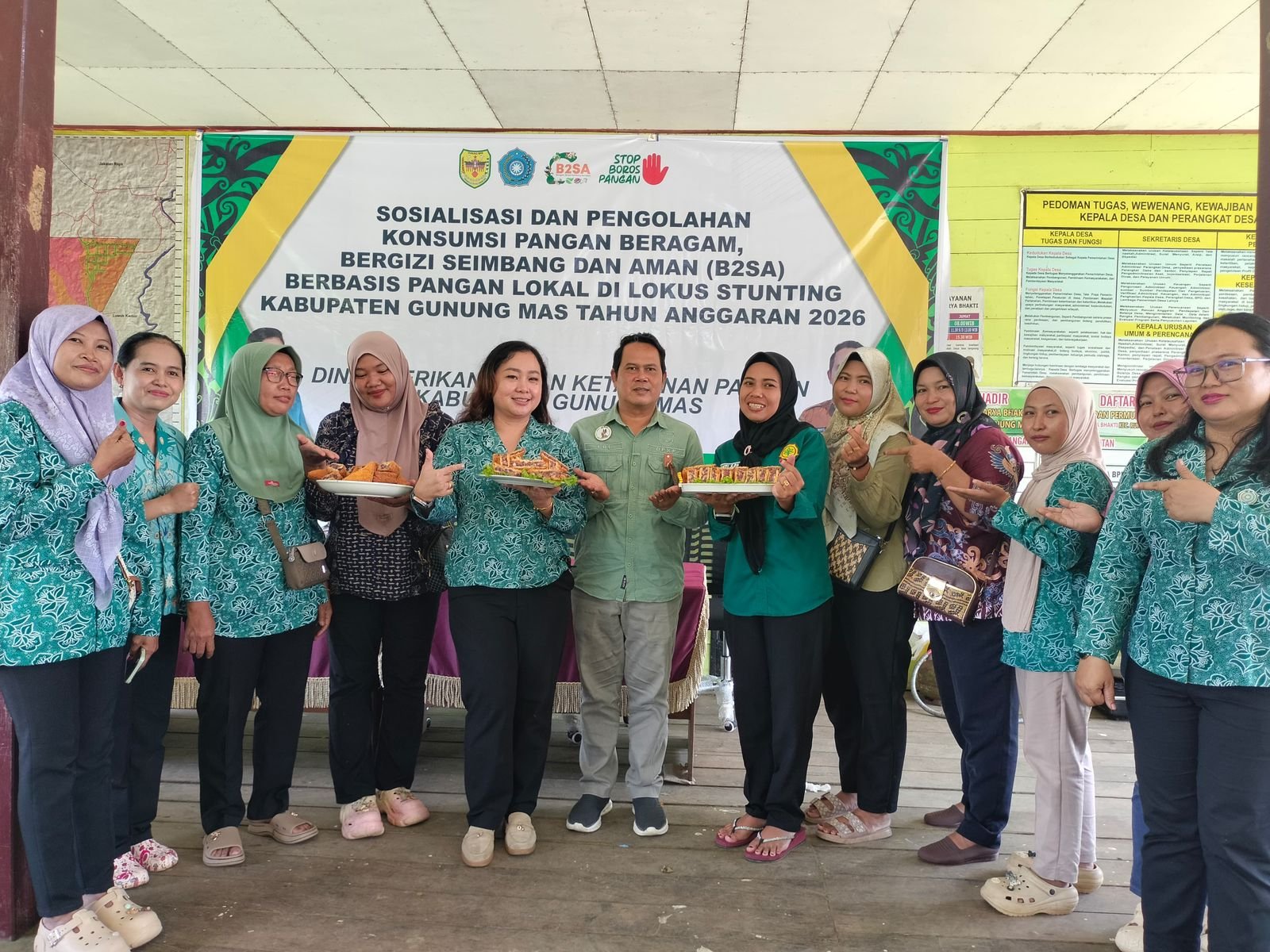 Sejumlah kader TP PKK Gunung Mas dan Dinas Perikanan berpose bersama sambil memegang hidangan olahan pangan lokal pada sosialisasi B2SA di Karya Bakti.