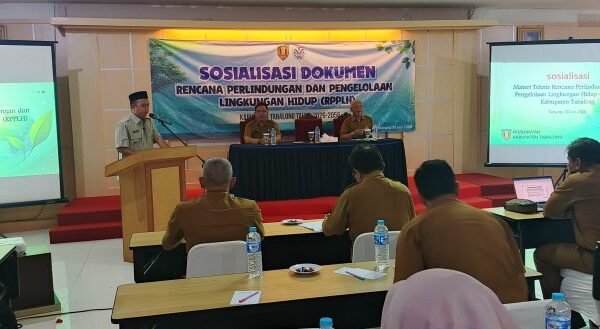 Wakil Bupati Tabalong berbicara di podium saat sosialisasi RPPLH 2026–2056, disaksikan peserta rapat dan layar presentasi di aula hotel.