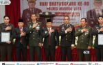 Para pejabat Murung Raya berdiri memberi hormat di depan banner Hari Bhayangkara ke-80 Polres Murung Raya pada acara syukuran di aula.