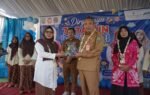 Pejabat daerah berseragam cokelat menyerahkan cenderamata kepada perwakilan guru di panggung HUT ke-76 IGTKI-PGRI Balangan.
