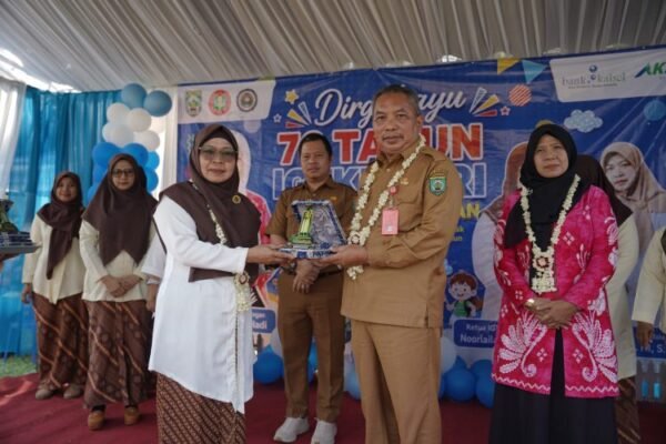 Pejabat daerah berseragam cokelat menyerahkan cenderamata kepada perwakilan guru di panggung HUT ke-76 IGTKI-PGRI Balangan.