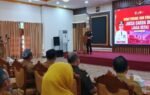 Ruang pertemuan menampilkan presentasi JAGA DESA di layar besar merah saat peserta duduk mengikuti sosialisasi di Tabalong.