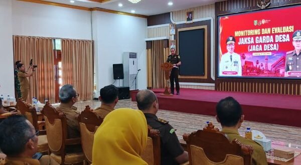 Ruang pertemuan menampilkan presentasi JAGA DESA di layar besar merah saat peserta duduk mengikuti sosialisasi di Tabalong.