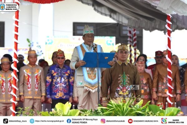 Heriyus membacakan sambutan di podium pada peringatan Hari Jadi ke-24 Kabupaten Murung Raya bersama pejabat berbusana adat.