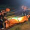 Petugas SAR berhelm oranye mengevakuasi Bakir dengan tandu oranye di tepi sungai pada malam hari setelah ditemukan tewas tenggelam.