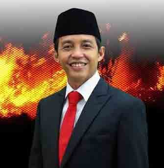 Menteri Kehutanan Raja Juli Antoni mengenakan jas hitam dan dasi merah di depan latar api, terkait pencabutan izin tiga perusahaan di Kalteng.