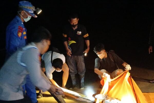Petugas dan warga mengevakuasi jenazah di pesisir Pantai Lunci pada malam hari, diduga terkait tenggelamnya KM Virgo Transport 8.