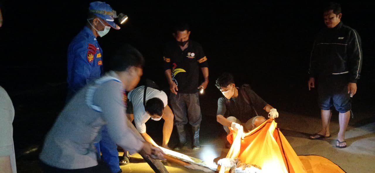 Petugas dan warga mengevakuasi jenazah di pesisir Pantai Lunci pada malam hari, diduga terkait tenggelamnya KM Virgo Transport 8.