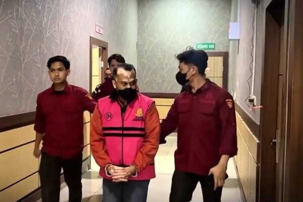 Di lorong, petugas mengawal pria berompi tahanan merah muda yang ditangkap sebagai DPO dugaan korupsi pabrik tepung ikan Kumai.