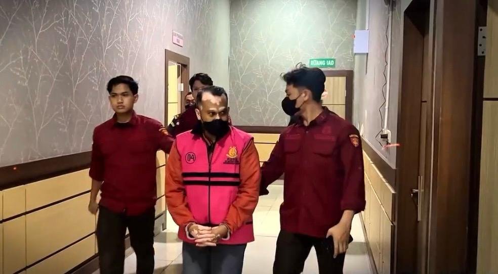 Di lorong, petugas mengawal pria berompi tahanan merah muda yang ditangkap sebagai DPO dugaan korupsi pabrik tepung ikan Kumai.